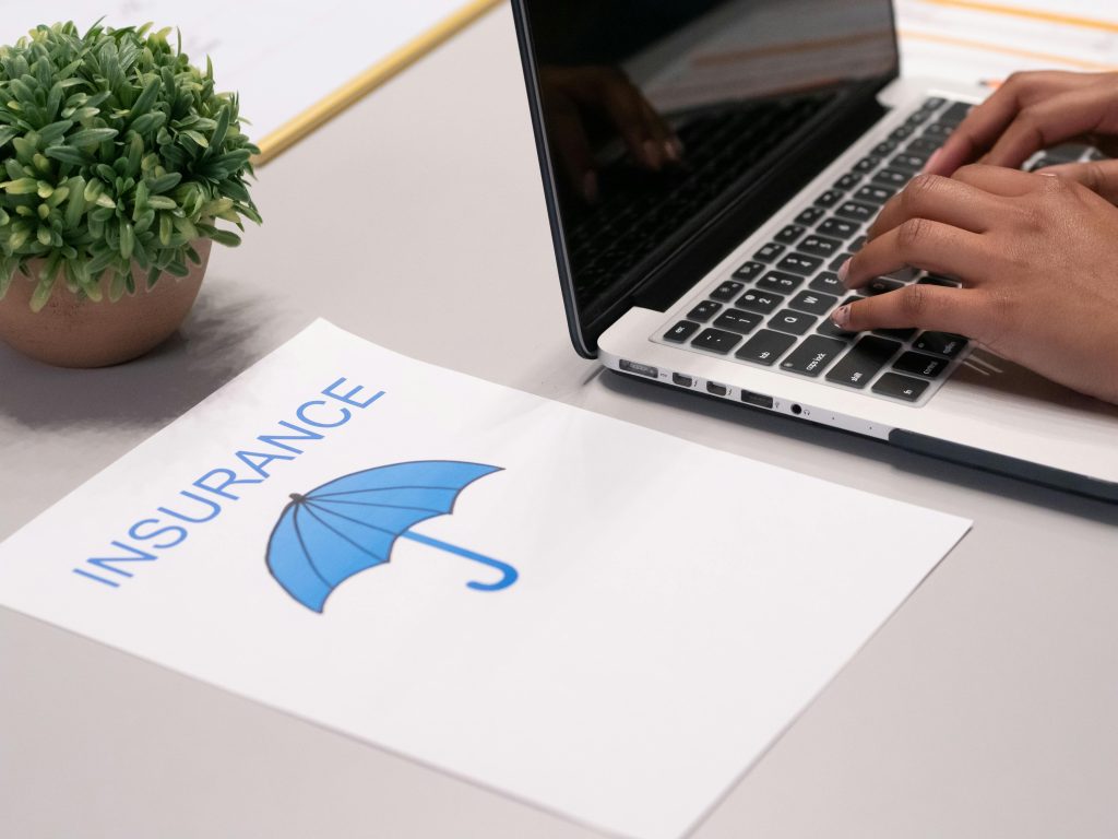 Corporate travel insurance document with blue umbrella symbol next to laptop on business workspace